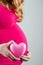 Pregnant girl hugs belly with her hand and holds heart