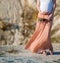 A pregnant girl in a long skirt against the backdrop of a desert steppe and mountains. Square crop