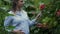 Pregnant girl sniffs a flower in the garden