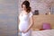 Pregnant gladden woman wearing white dress holding belly.