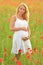 Pregnant happy woman in a flowering poppy field outdoors