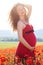 Pregnant happy woman in a poppy field outdoors