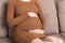 Pregnant Lady Having Massaging Lower belly Sitting On Sofa Indoor. Pregnancy Problems Concept. Maternity healthcare