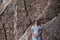 Pregnant millennial woman in blue dress stands among the rocks on the seashore, hugging belly