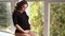 Pregnant moman sits in front of big window. Model dressed in black bodysuit. She put her hand on the belly. Happy future