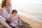 Pregnant mother and daughter playing in beach sand