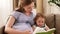 Pregnant mother and daughter reading book at home