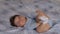 Pregnant Mother laying with her baby son on the bedroom bed playing and having fun - Asian mixed ethnicity child Boy