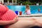 Pregnant mother relax by the pool while kids play with water