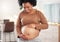 Pregnant, stomach and smile of black woman in home for maternity leave, health and wellness. Pregnancy, prenatal