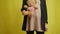 Pregnant unrecognizable woman standing with teddy bear at yellow background stroking belly. Front view happy young