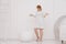 A pregnant woman at 9 months stands near a huge broken eggshell and waits for the baby to appear on a white background