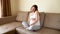 Pregnant woman applying headphones in the sofa. Expectant mother listening music and dancing in light bedroom. Pregnant female giv