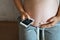 Pregnant woman attached the smartphone to her stomach checking the heartbeat using a special application.