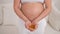 A pregnant woman with a bare belly holds a handful of vitamins. Transparent golden pills. Vitamin D for the expectant