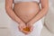 A pregnant woman with a bare belly holds a handful of vitamins. Transparent golden pills. Vitamin D for the expectant