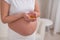 A pregnant woman with a bare belly holds a handful of vitamins. Transparent golden pills. Vitamin D for the expectant