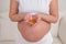 A pregnant woman with a bare belly holds a handful of vitamins. Transparent golden pills. Vitamin D for the expectant