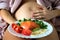 pregnant woman with beautiful pregnancy belly touching her stomach and holding delicious plate with healthy food ingredients