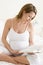 Pregnant woman in bedroom reading book