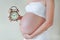 Pregnant woman with big belly in white underwear holding vintage alarm clock. Pregnancy waiting baby concept