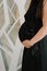 A pregnant woman in a black dress holds her hands on her stomach. Happy pregnancy