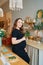 a pregnant woman in a black dress in the kitchen of the house.