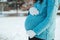 Pregnant woman in blue sweater touching big belly with hands. Warm clothes in cold weather. Pregnancy time