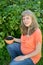 The pregnant woman with a bowl of black currant in a garden