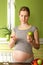 Pregnant woman choosing between pills and apple