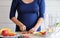 Pregnant woman cooking and cutting fruit for fruit blender