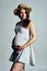 Pregnant woman in country style summer dress and straw hat standing touching her belly