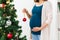 Pregnant woman decorating christmas tree