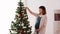 Pregnant woman decorating christmas tree at home