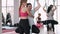 A pregnant woman is doing aerial yoga with a fitness instructor