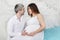 Pregnant woman in dress and man look at each other