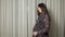 Pregnant woman in dress strokes belly with happy smile