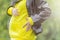 Pregnant woman dressed a yellow hoodie and black jacket holds hands on belly on a green background.