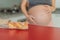 Pregnant woman eating bread in the kitchen. Exploring the impact of gluten during pregnancy: understanding the potential