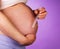 Pregnant woman with empty test tube in hand on purple.