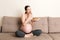 Pregnant woman enjoys eating cookies resting on the sofa at home. Unhealthy sweet pastry during pregnancy concept
