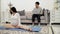 Pregnant woman exercise on floor and husband working on couch