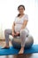 Pregnant woman, expectant mother with big belly in late pregnancy, smiling looking at camera while exercising on fitball