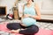 Pregnant Woman Feeling Baby Moves While Sitting On Yoga Mat