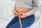 Pregnant woman feeling curious measuring waistline