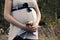 Pregnant woman in field with a bunch of wild flowers under belly