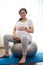 Pregnant woman on fitball, holding her belly, smiling looking at camera, enjoying prenatal fitness in pregnancy time