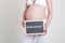 Pregnant woman with German word midwife on blackboard