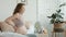 Pregnant woman getting up in bedroom. Closeup smiling mother stroking belly.