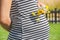 Pregnant woman hands give yellow wild flowers with sunny meadow and blue sky.Romantic and love feelings.